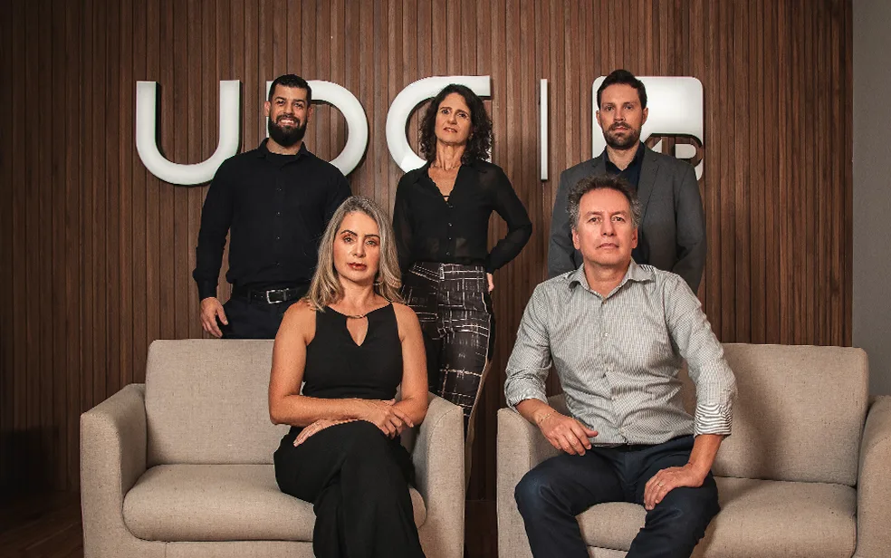 Executivos apertando as mãos em escritório representando a fusão entre Blue3 e UDG Investimentos.